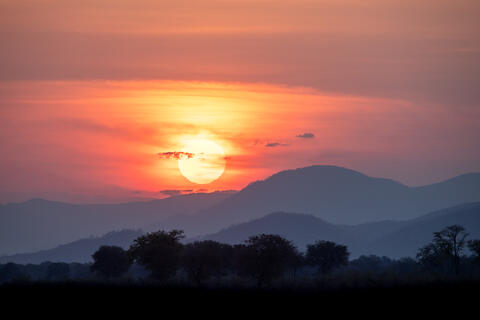 The sun sets over the hills in lower zambezi national park in Zambia, Africa. 