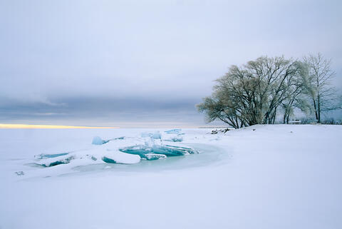 Late afternoon winter view along lake michigan near escanaba.  Snow and ice sheets piled on shore are seen 