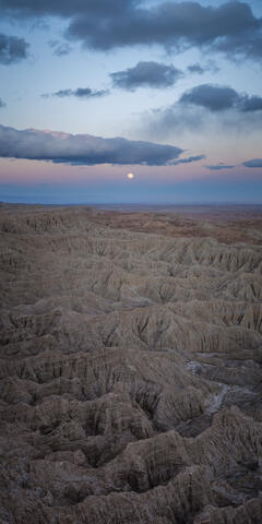 The full moon rises over the badlands of Anza-borregoo in california