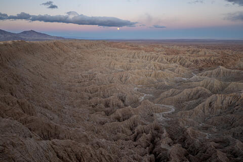 a Full moon rises over the badlands at font's point in Anza-borrego desert state park in california