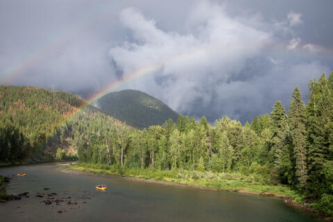 A rainbow is seen in the background as Rafters float down the middle fork of the flathead river, Montana, usa