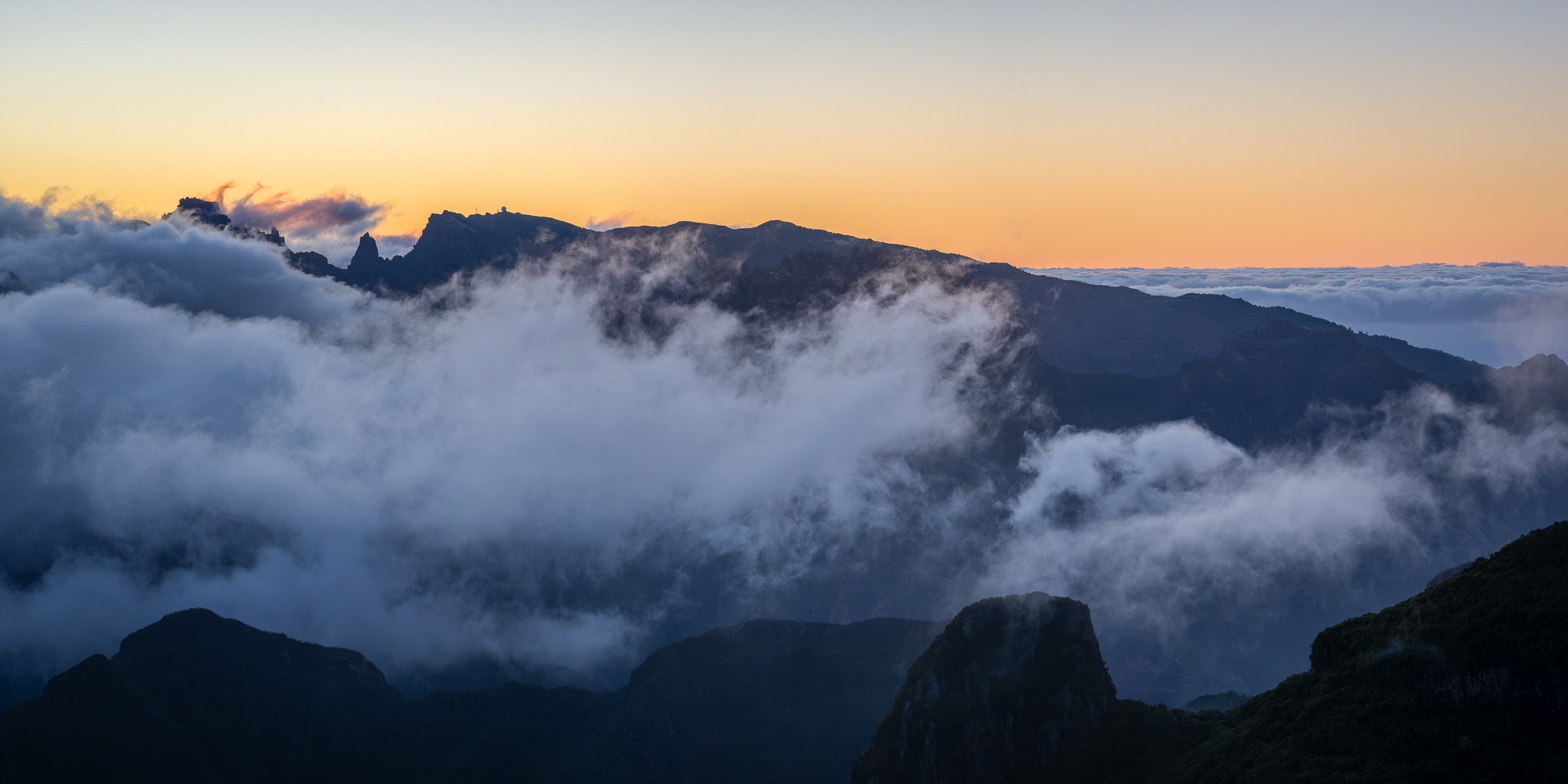 Sunrise from Bica da Cana peak Pico Ruivo and pico do Areeiro are seen at sunrise from the peak of Bica da Cana in Madeira, Portugal from above the clouds.